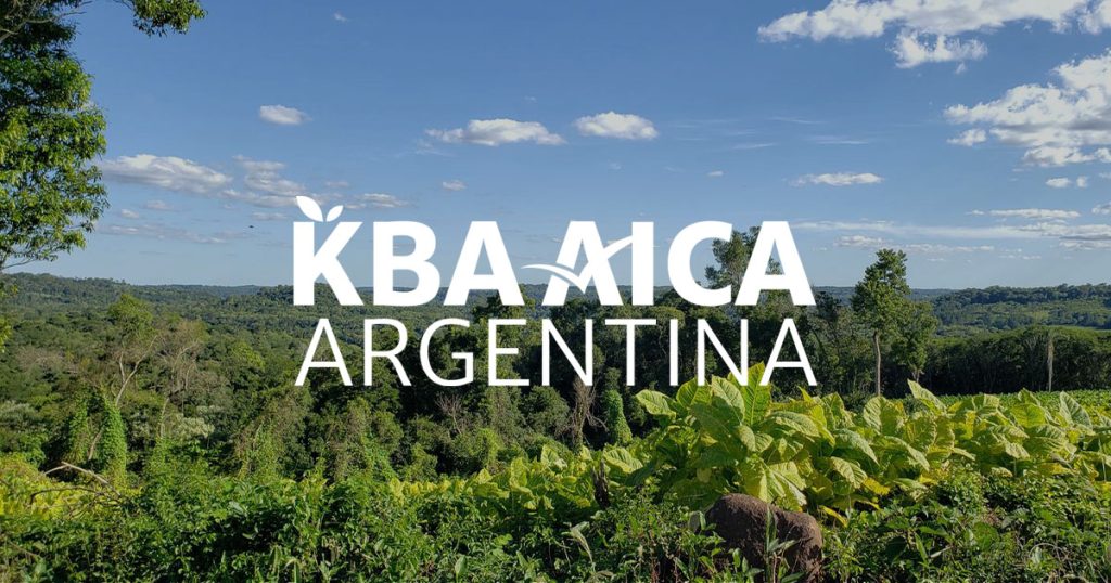 Logotipo de KBA AICA Argentina sobre un fondo fotográfico de un paisaje de la KBA Campo Viera y Campo Grande.